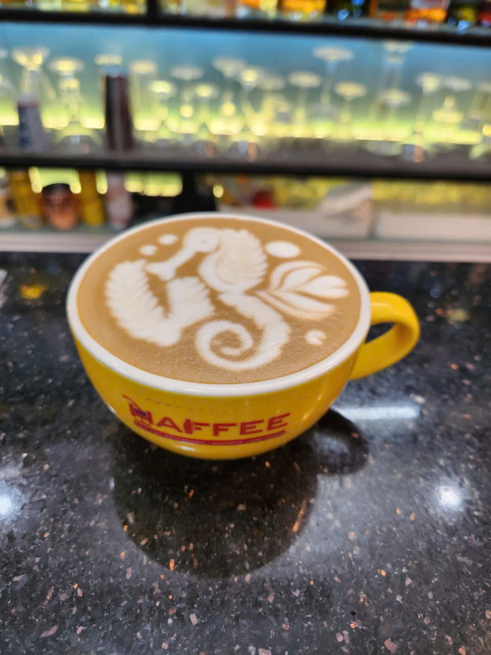 Latte art cá ngựa với thân cong và đuôi xoắn, thể hiện kỹ thuật rót sữa chính xác và tinh tế